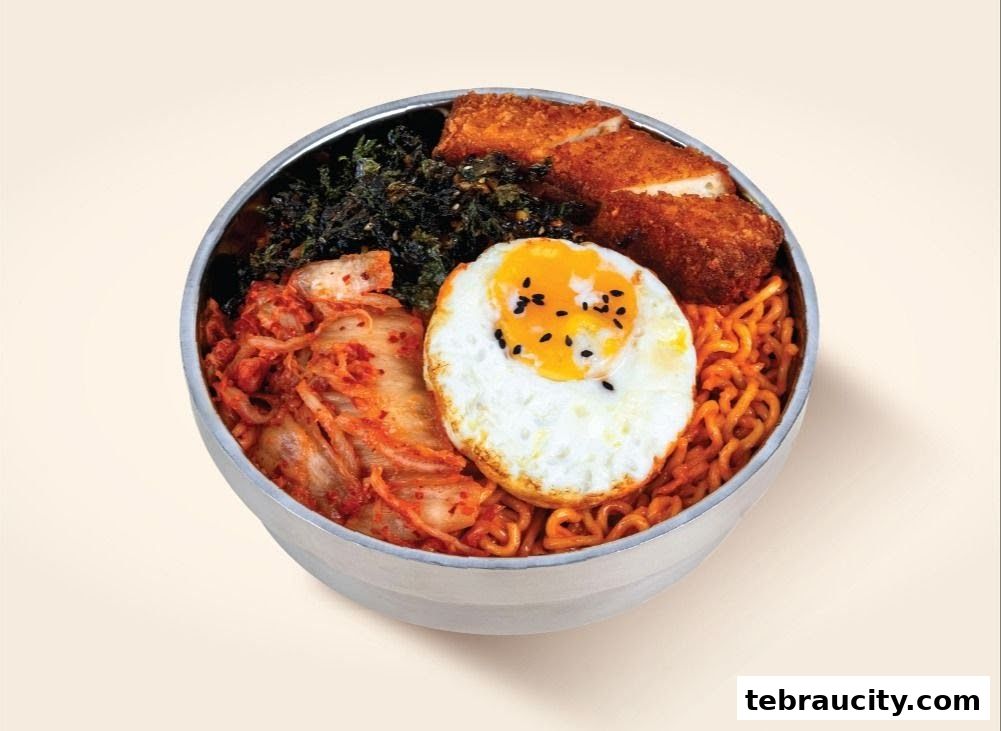 A delicious bowl of ramen with fried chicken, a sunny-side-up egg, kimchi, and seaweed.