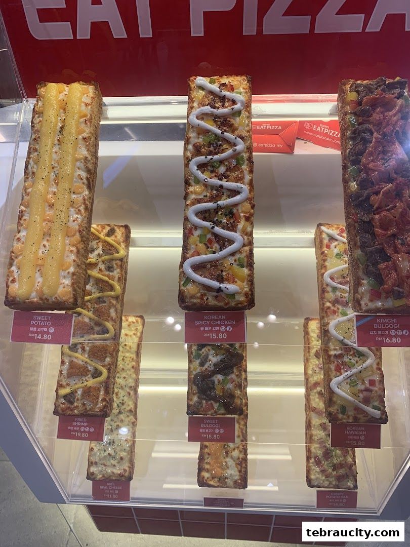 A display of various rectangular pizzas with different toppings and prices.