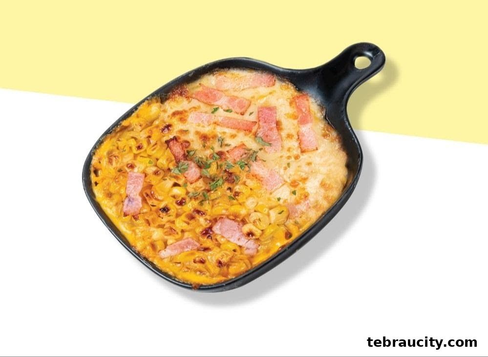 A close-up shot of a baked pasta dish with cheese and bacon in a black serving pan.