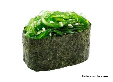 A close-up shot of a single sushi roll with seaweed and sesame seeds.