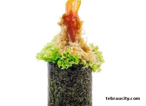 A close-up of a sushi roll with tempura shrimp, lettuce, and crispy toppings.