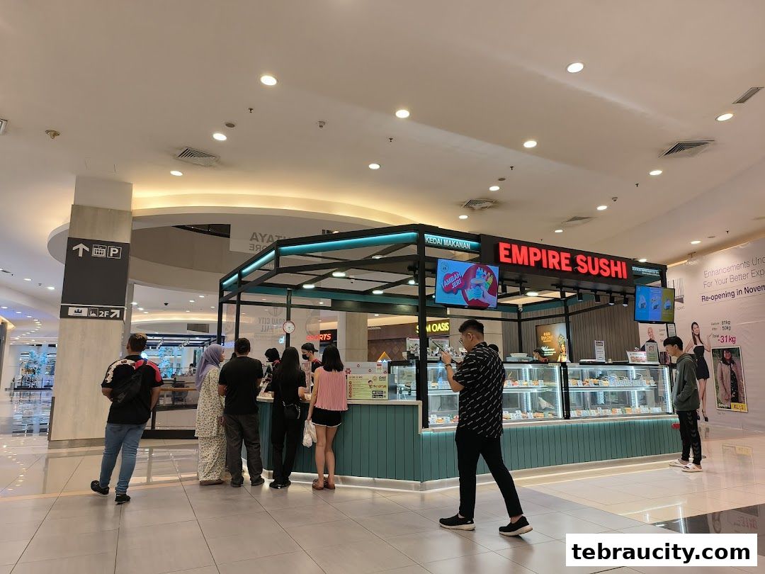 People are queuing at the Empire Sushi counter in a shopping mall.