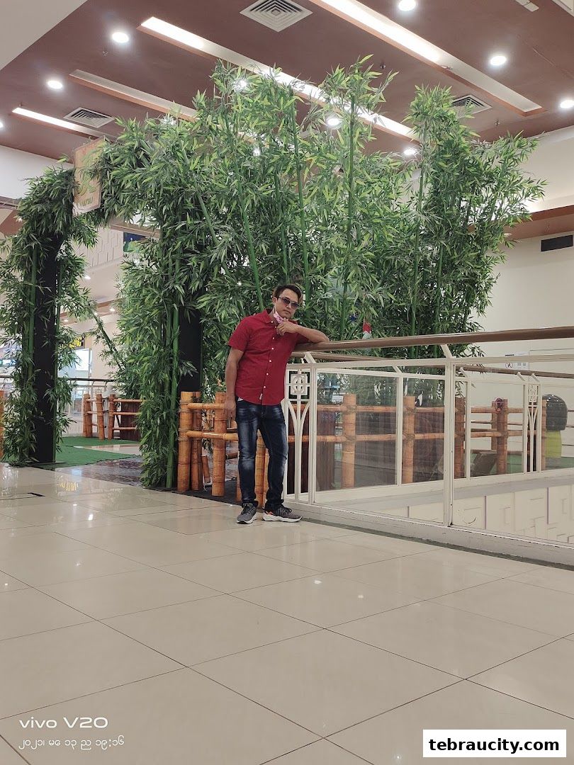 A man poses in front of a large bamboo display in a shopping mall.