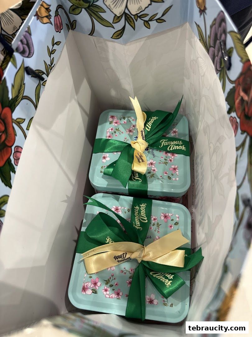 Two beautifully wrapped Famous Amos cookie tins inside a floral patterned shopping bag.