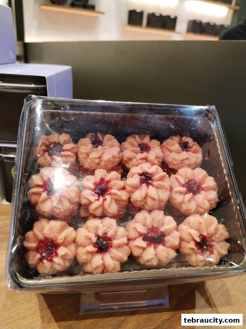 A clear plastic container filled with flower-shaped cookies with a jam filling.