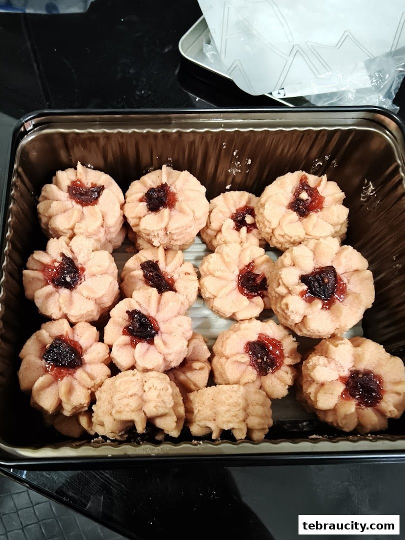 A close-up view of a tin filled with delicious-looking jam-filled cookies.