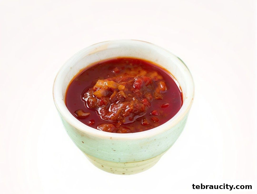 A close-up shot of a bowl filled with a rich, red, chunky sauce or condiment.