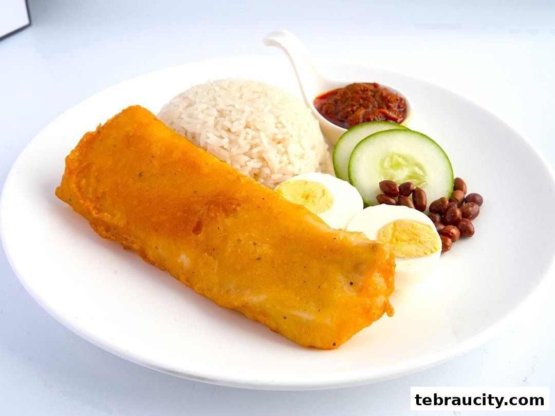 A plate of Nasi Lemak with fried fish, rice, egg, cucumber, peanuts, and sambal.