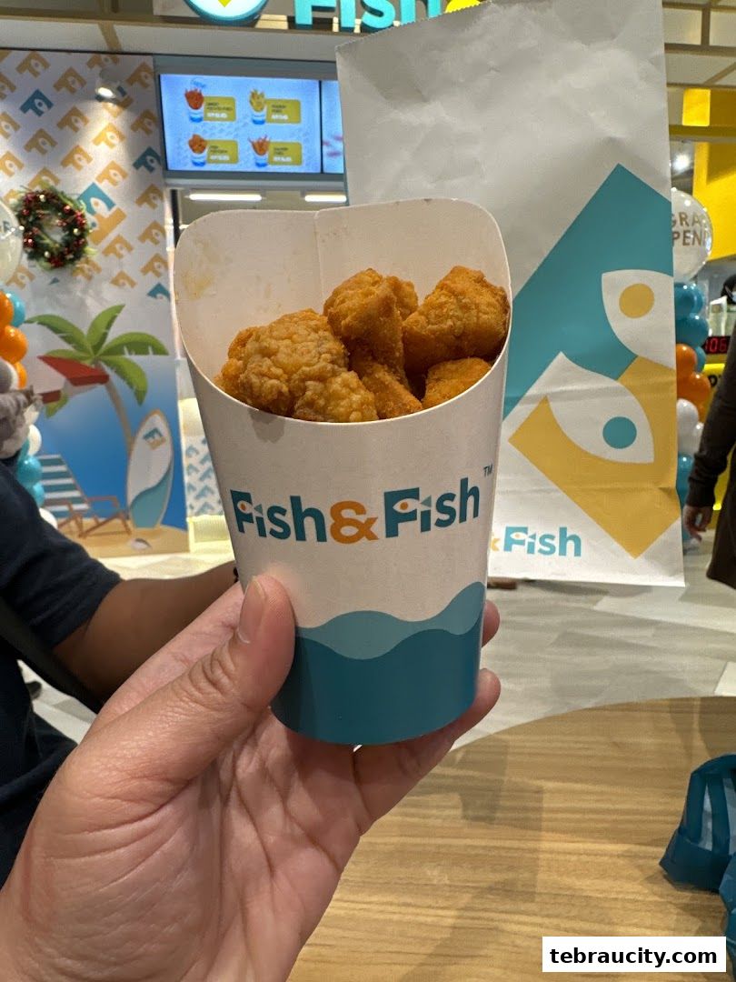 A hand holds a cup of crispy fried fish bites from Fish & Fish.