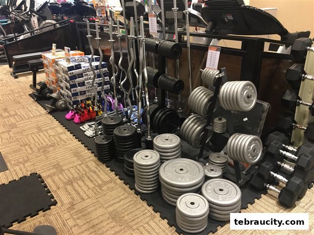 A wide selection of weightlifting equipment, including dumbbells, barbells, and weight plates, is displayed.