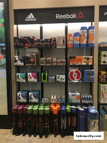 A display of fitness equipment including yoga mats, weights, and resistance bands from brands like Adidas and Reebok.