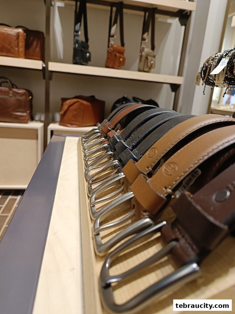 A display of leather belts with various buckle styles and colors inside a retail store.