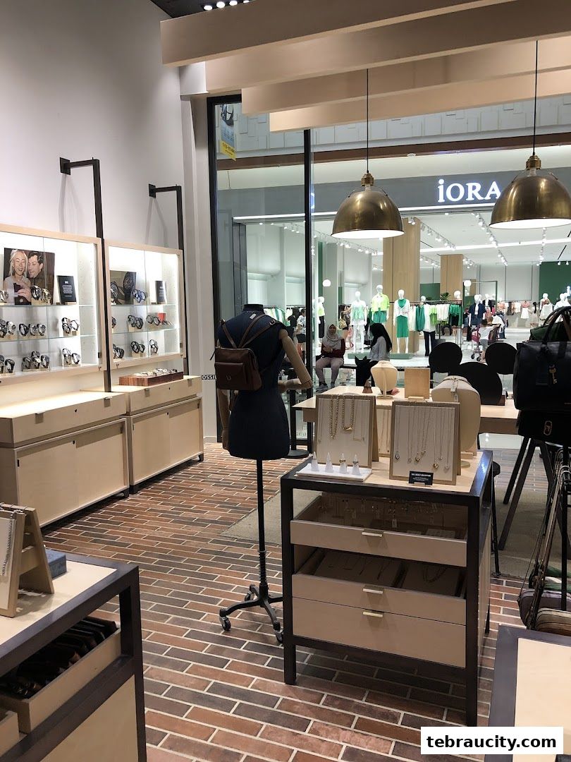 Interior view of a Fossil store showcasing watches and jewelry, with other shops visible through the window.