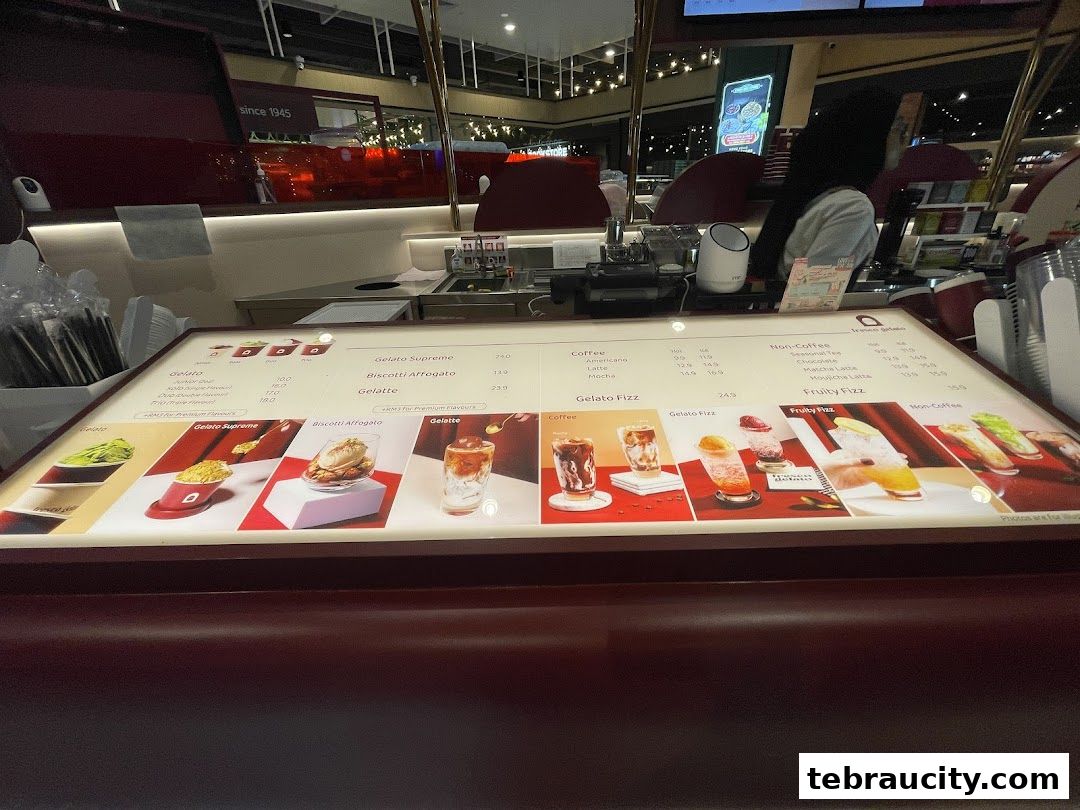 A brightly lit menu display for Fresco Gelato, showcasing various gelato and coffee drinks.