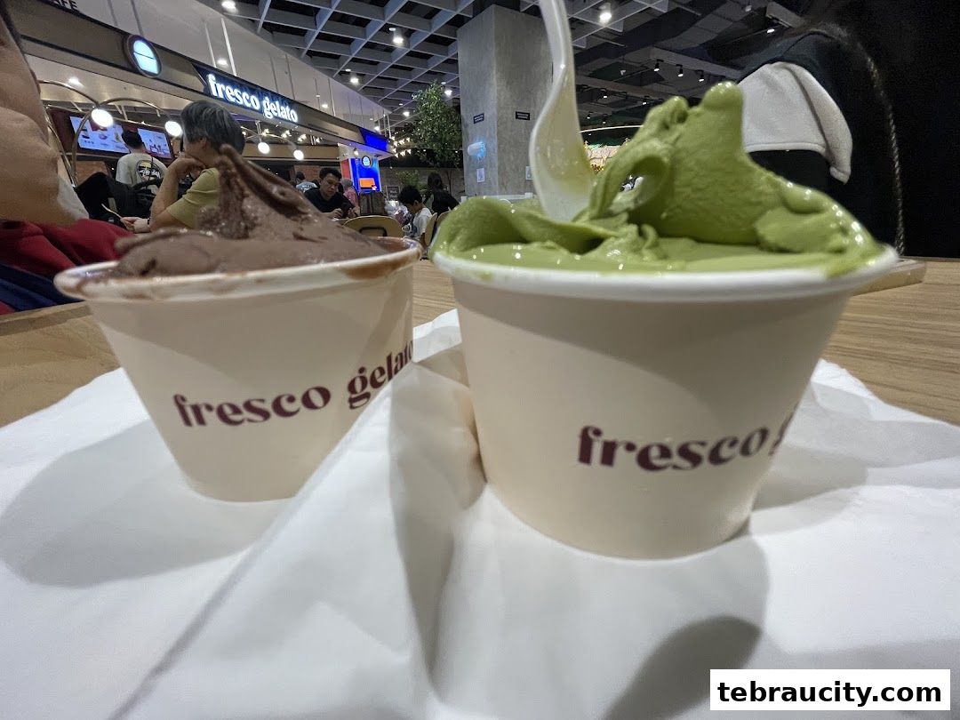 Two cups of gelato, one chocolate and one matcha, are displayed on a white napkin.