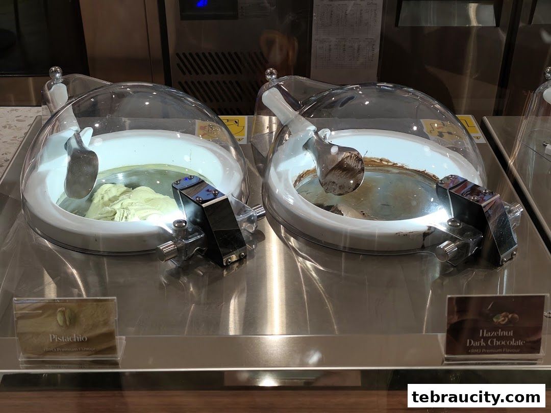 Two gelato display containers, one with pistachio and the other with hazelnut dark chocolate.