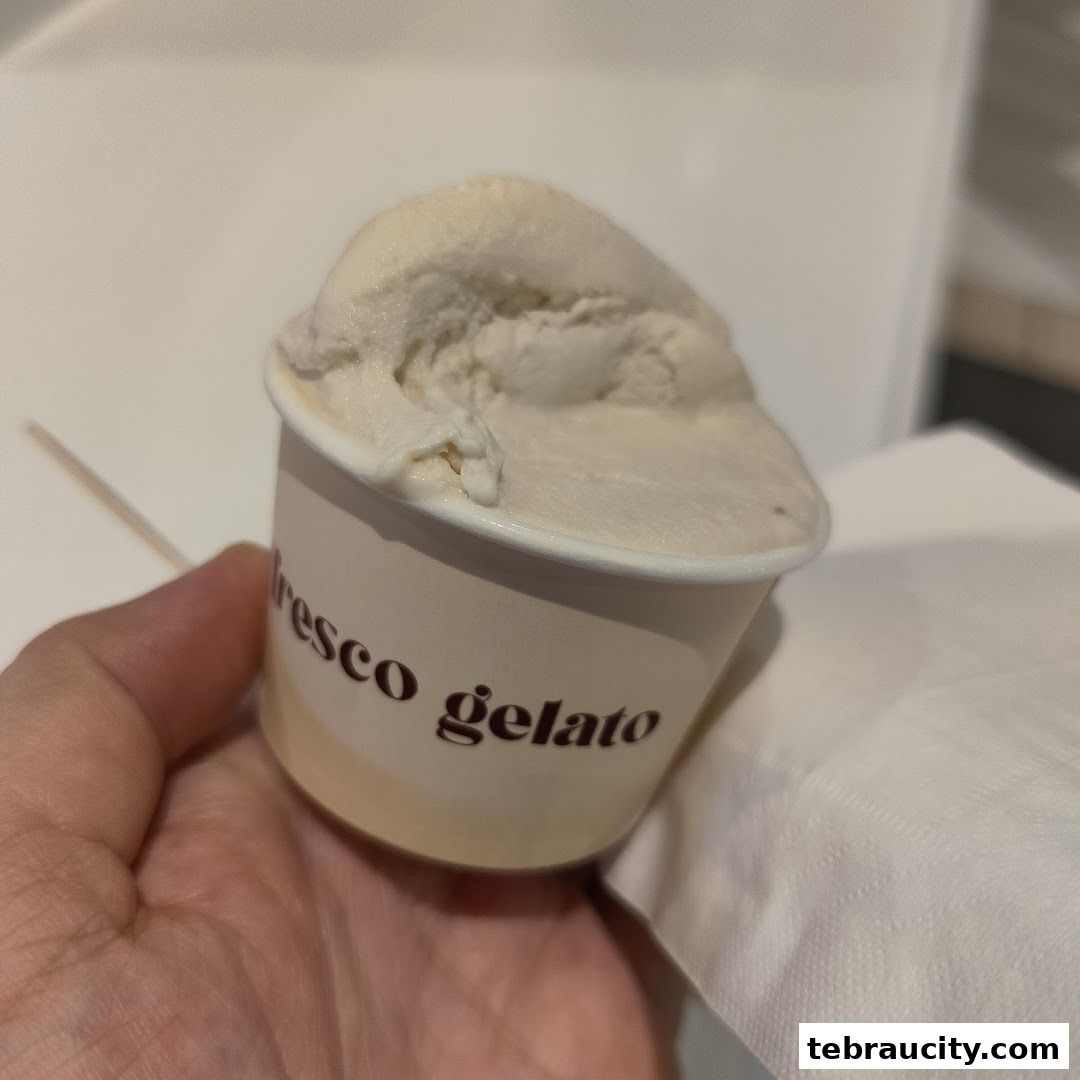 A hand holds a cup of creamy gelato from Fresco Gelato.