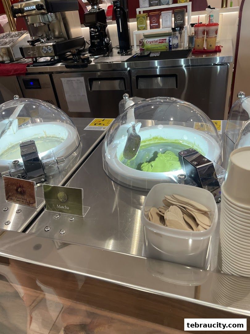 Gelato display with matcha and hazelnut flavors, coffee machine, and cups.