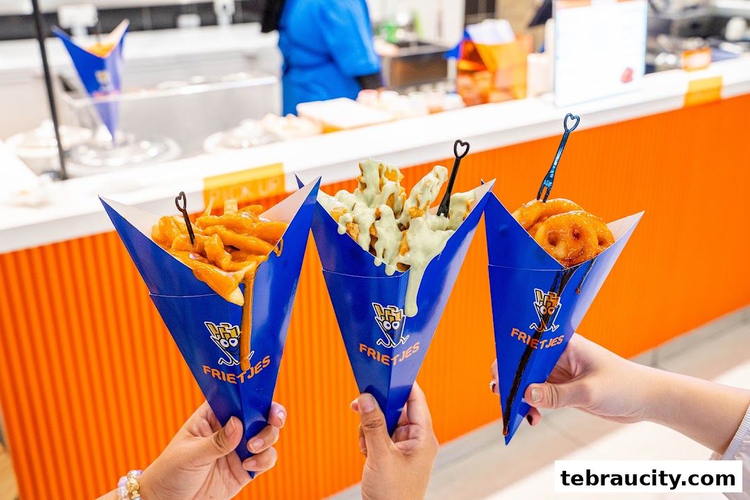 Three cones of loaded fries with different toppings are held up in front of an orange counter.