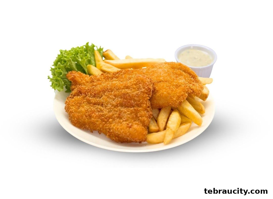 A plate of crispy fried fish and chips with a side of tartar sauce and lettuce.