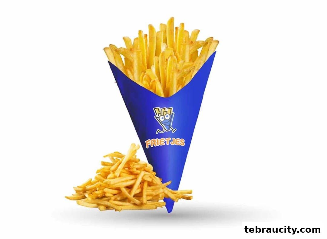 A cone of crispy golden fries with a pile of fries next to it.