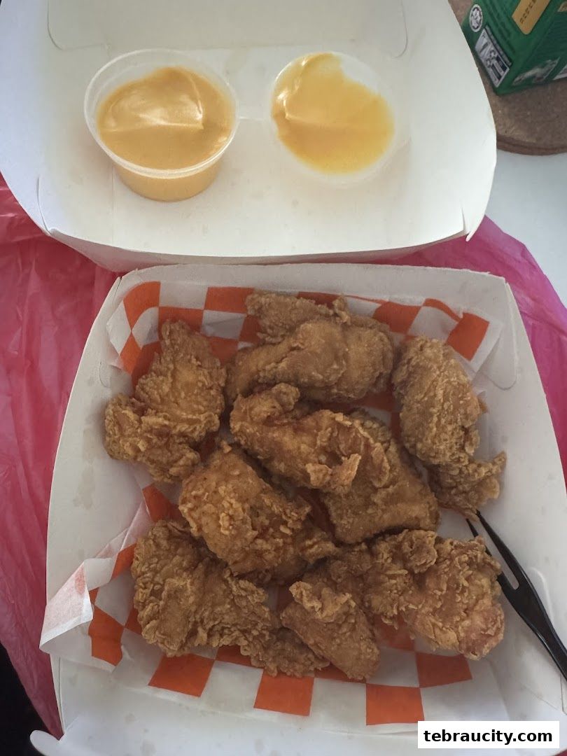 A box of crispy fried chicken wings with two dipping sauces.