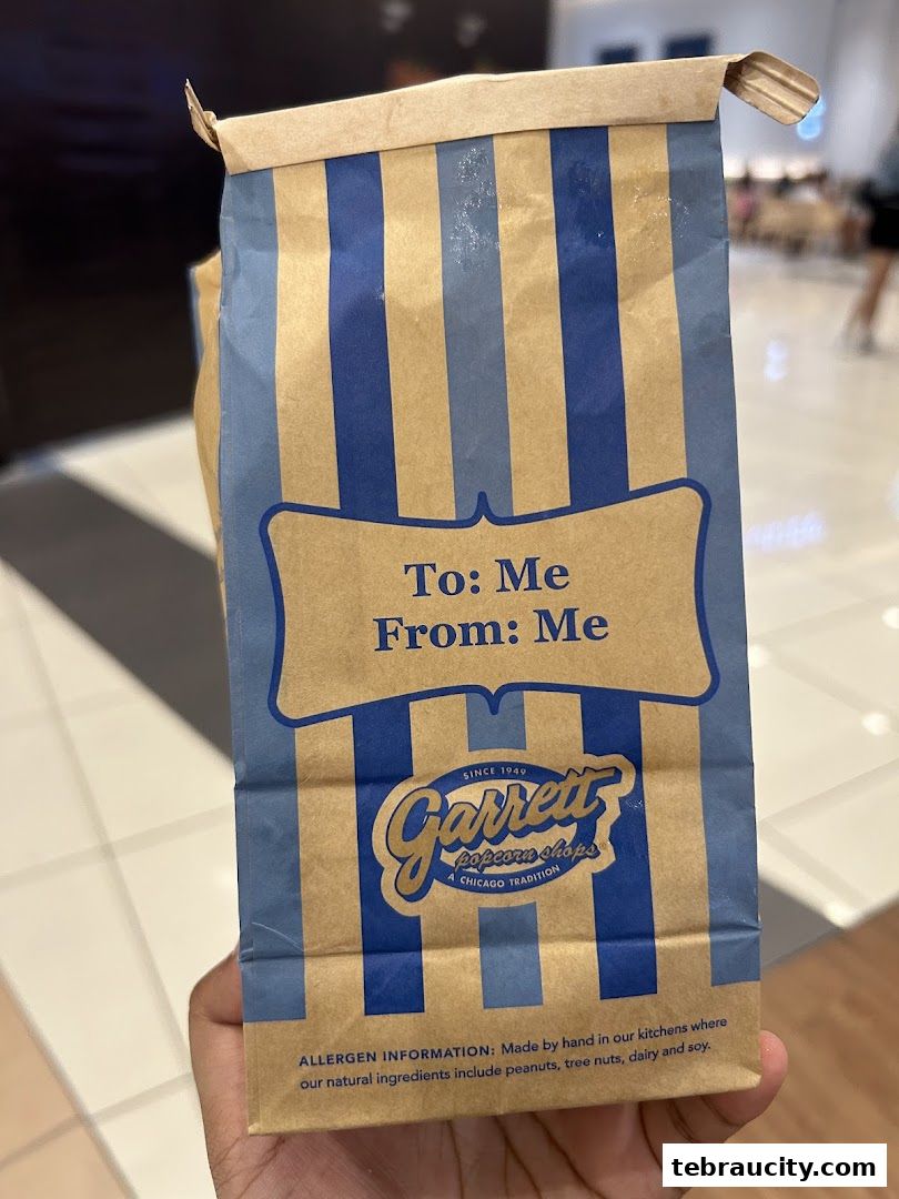 A hand holds a paper bag from Garrett Popcorn Shops with a personalized message.
