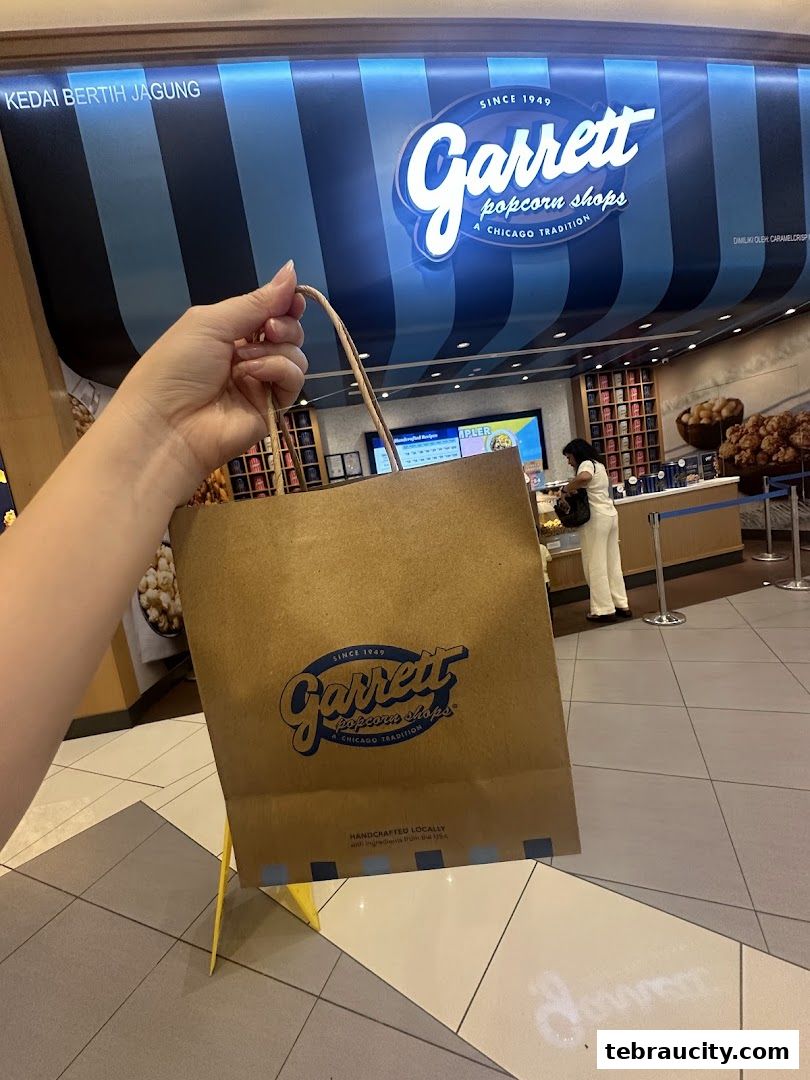 A person holds a Garrett Popcorn Shops bag in front of the store.