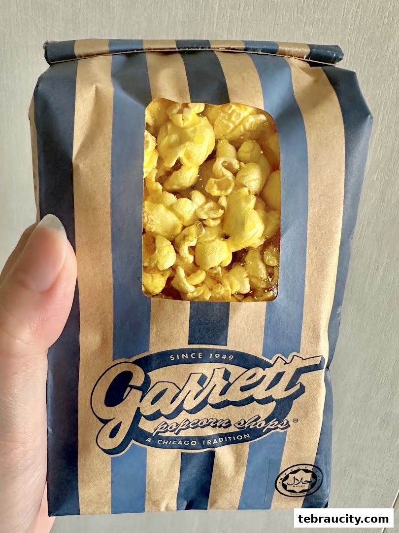 A hand holds a bag of Garrett Popcorn Shops popcorn with a window showing the product.