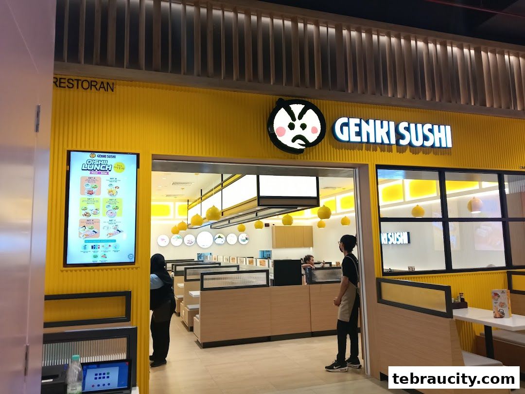 The bright yellow exterior of Genki Sushi restaurant with its logo and an illuminated lunch menu.