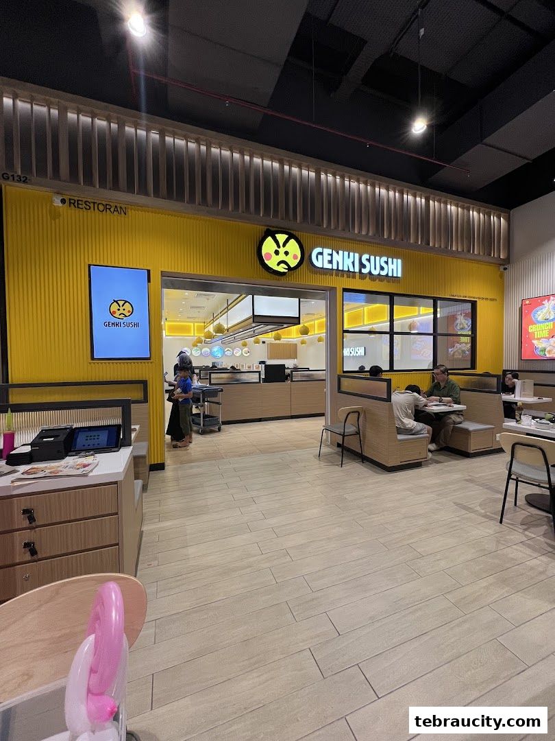 The bright yellow exterior of Genki Sushi with customers dining inside.