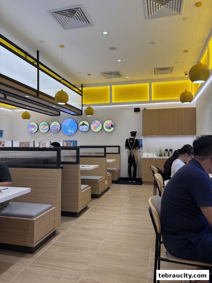 Interior of a modern sushi restaurant with booth seating and a staff member.