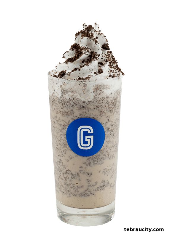 A tall glass of cookies and cream milkshake topped with whipped cream and cookie crumbles.