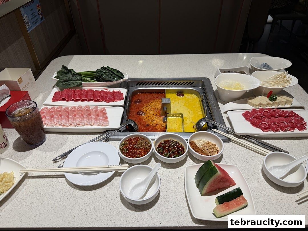 A table laden with various ingredients for hot pot, including thinly sliced meats, vegetables, and dipping sauces.