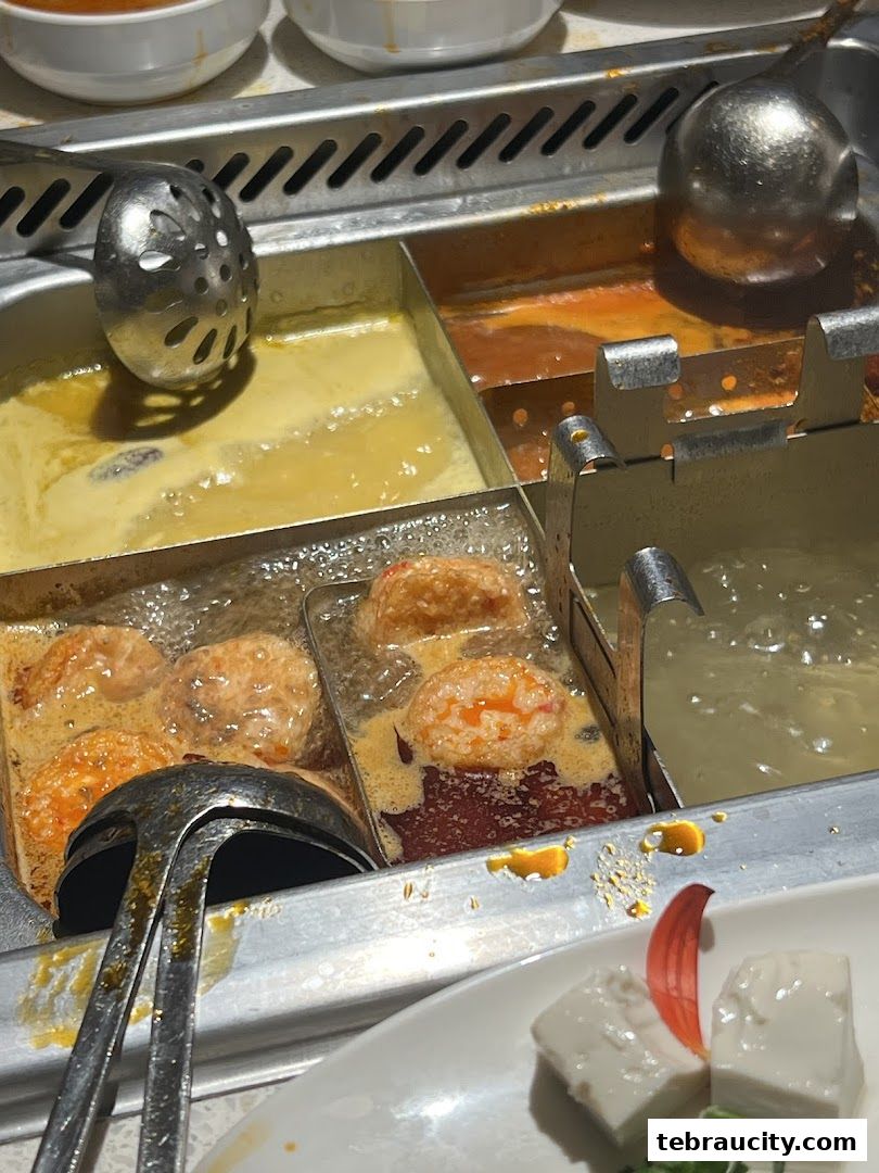 A close-up of a hot pot with various broths and ingredients being cooked.