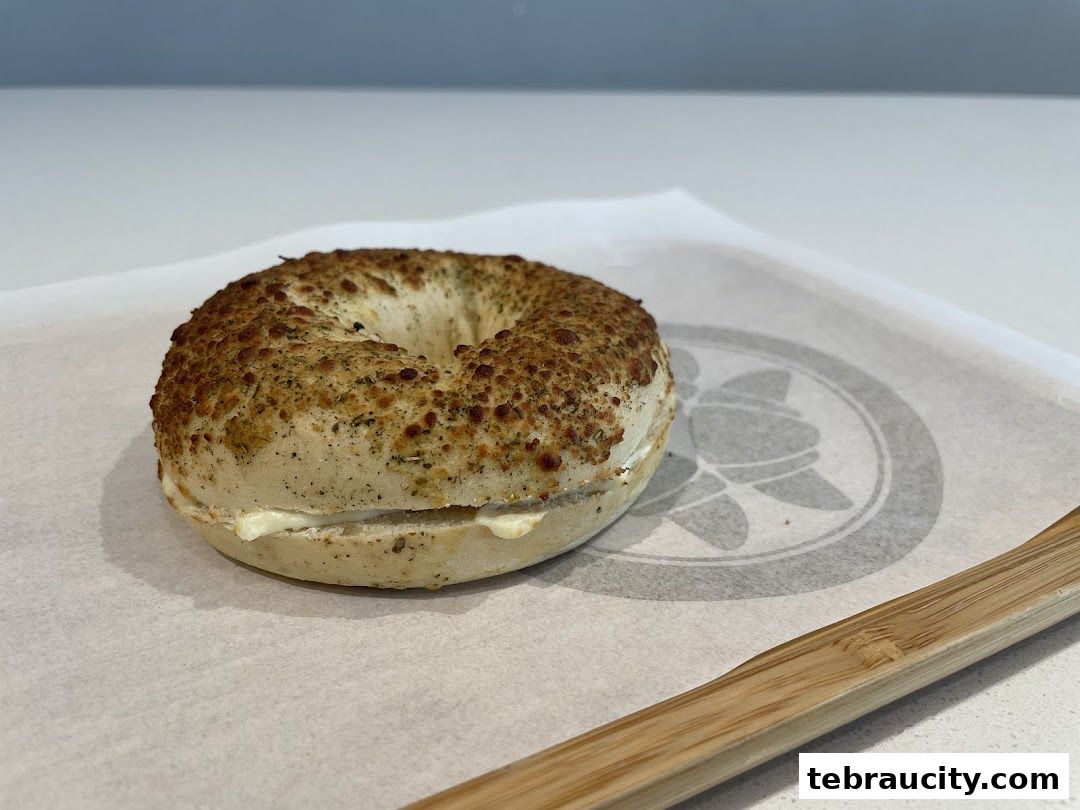 A close-up shot of a savory bagel with cream cheese filling on parchment paper.