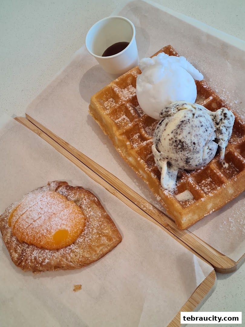 A delicious waffle with ice cream and a pastry with fruit filling, served on wooden boards.
