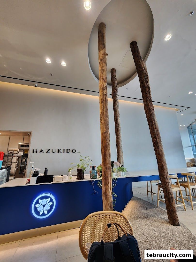 Interior view of Hazu Bakery Cafe with a blue counter, wooden pillars, and seating.