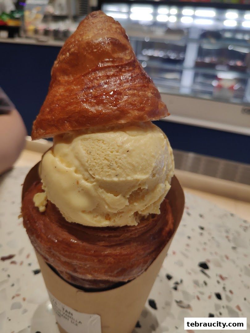 A close-up of a pastry filled with ice cream, presented in a paper cone.