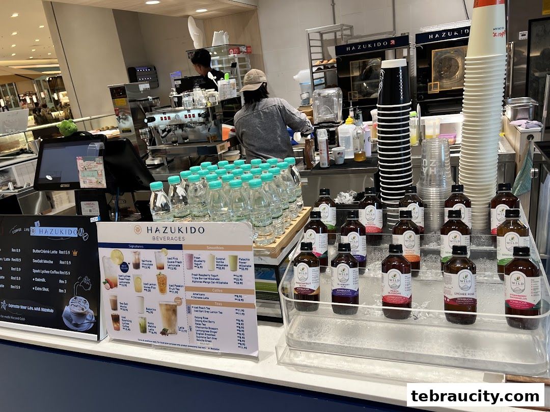 A display of bottled beverages and a menu at a cafe counter with staff in the background.
