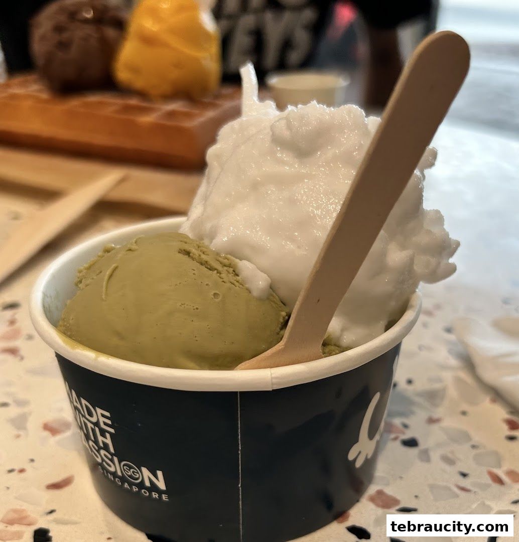 A cup of ice cream with green tea and white flavors, served with a wooden spoon.