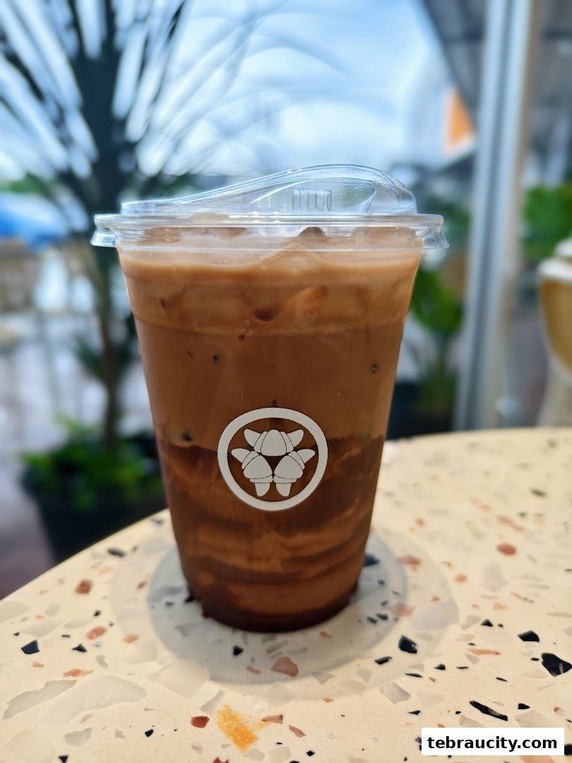 A refreshing iced coffee with layered chocolate and milk, featuring the Hazu Bakery Cafe logo.