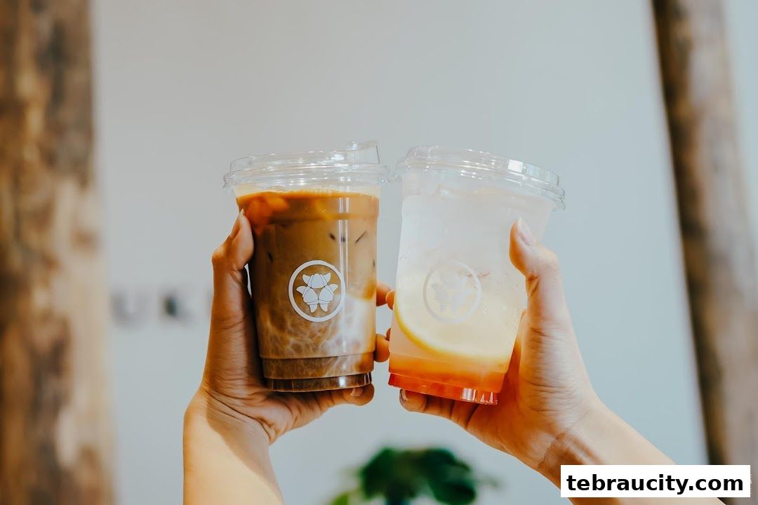 Two hands holding iced coffee and a refreshing drink with lemon.