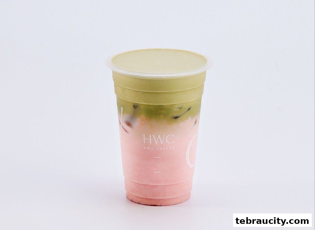 A layered pink and green beverage in a clear plastic cup with the HWC Coffee logo.