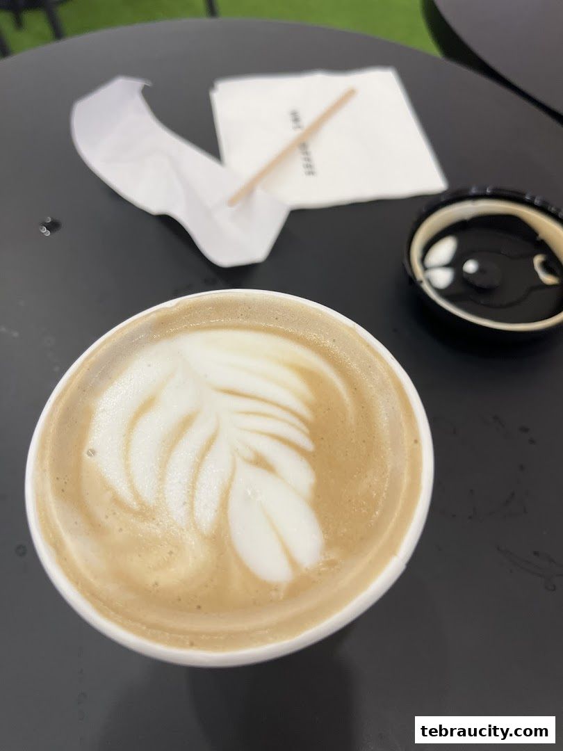 A close-up of a latte with intricate foam art on a dark table.