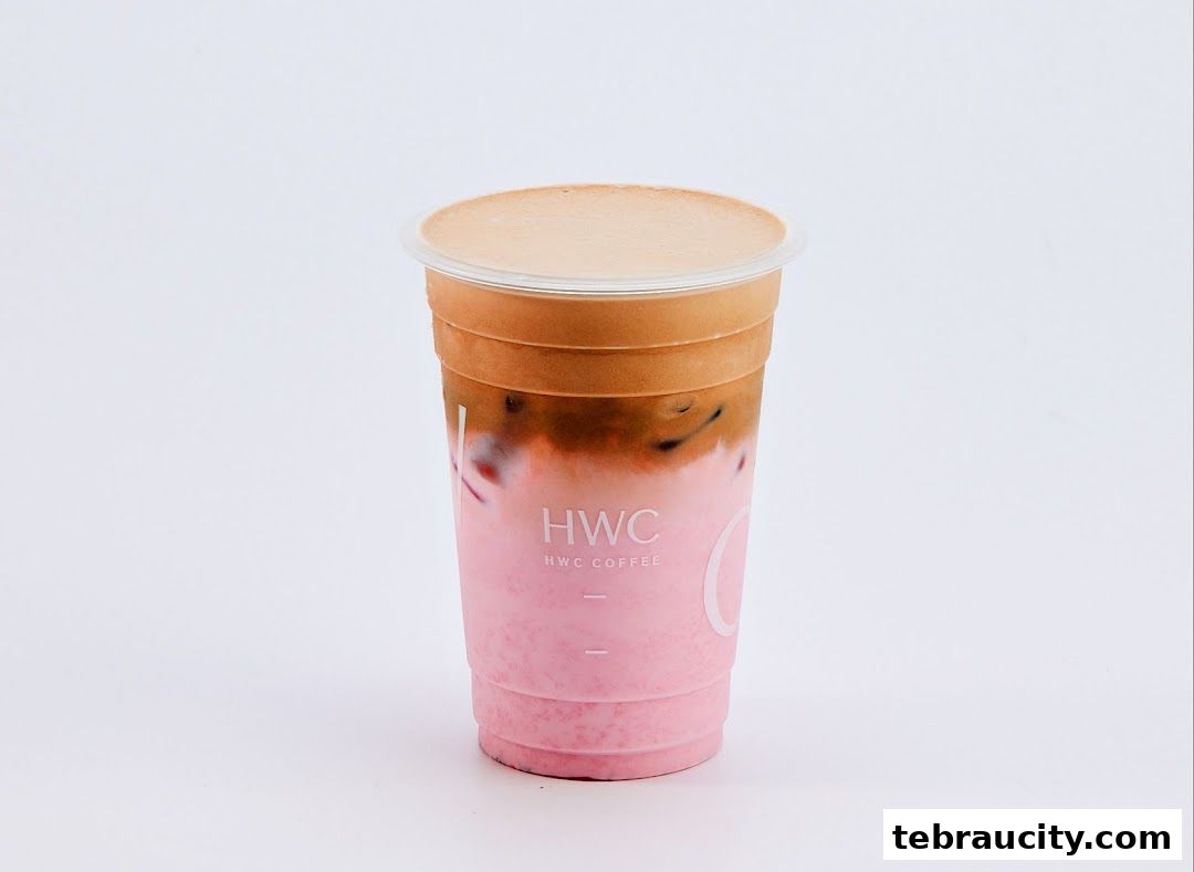 A refreshing pink and brown layered coffee drink in a clear plastic cup with the HWC Coffee logo.
