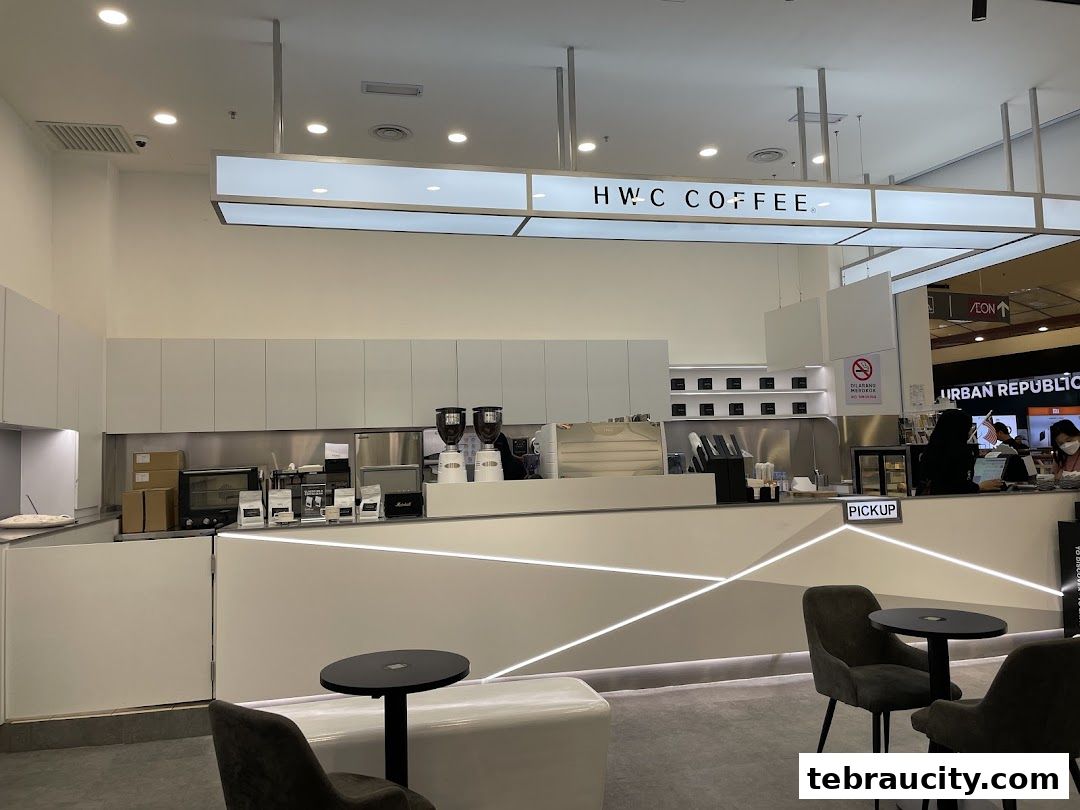 Modern coffee shop interior with a clean white counter, seating, and HWC Coffee branding.