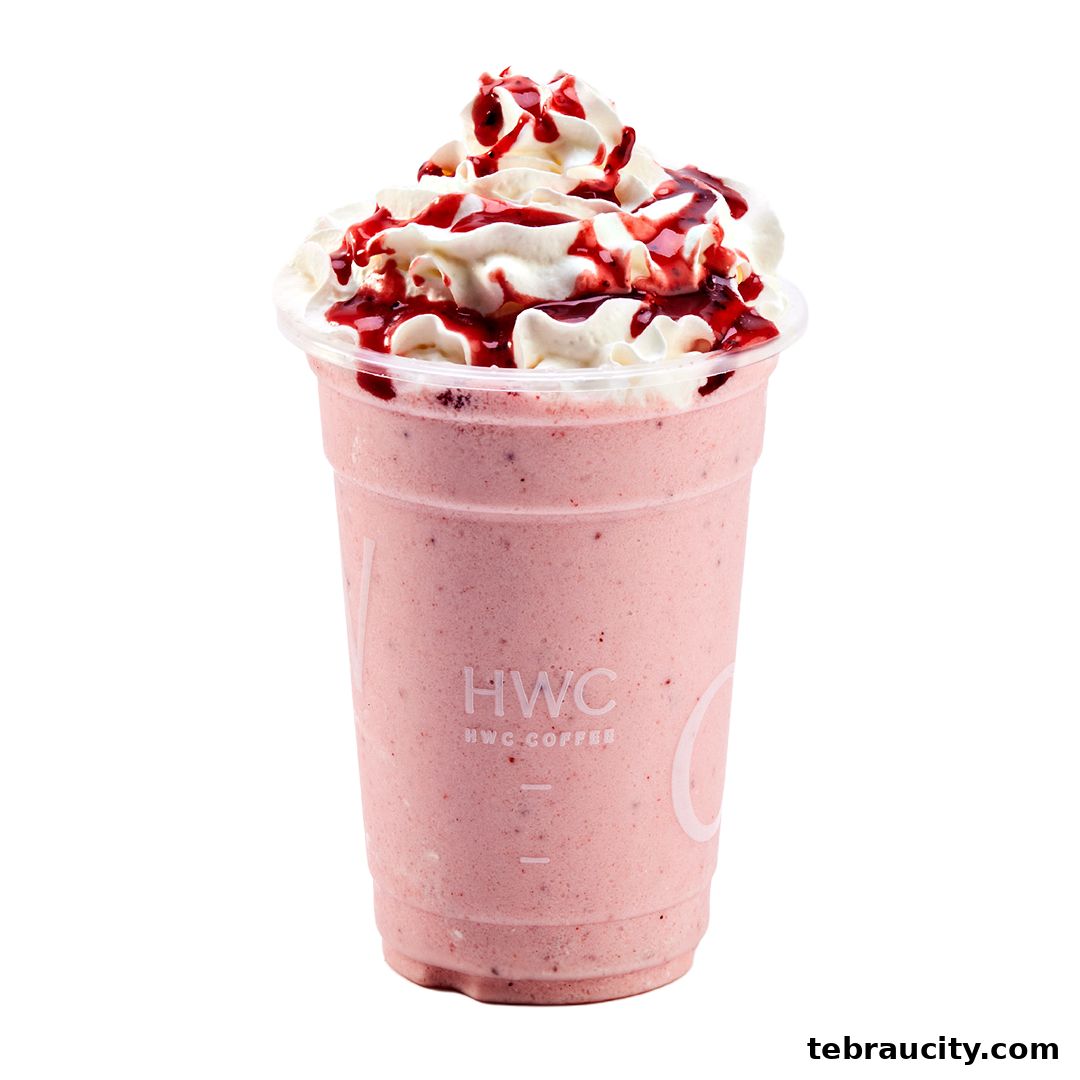 A close-up of a strawberry smoothie with whipped cream and berry drizzle from HWC Coffee.