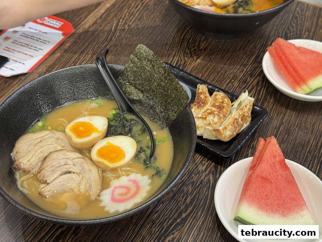 A delicious bowl of ramen with pork, egg, and seaweed, served with gyoza and watermelon.