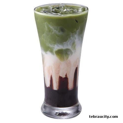 A tall glass filled with a layered matcha drink with milk and chocolate syrup.